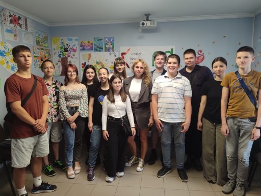 Gruppenfoto von Jugendlichen und Erwachsenen in einem bunten Raum mit Kunstwerken an den Wänden.